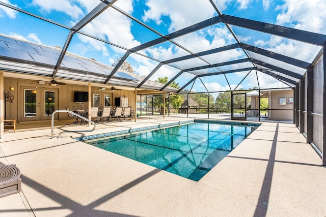 view of swimming pool featuring a patio, ceiling fan, french doors, and glass enclosure