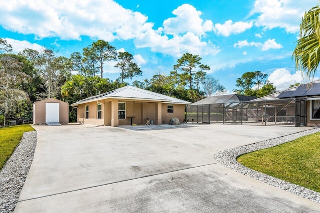 view of front of house with a patio, a pool, a storage shed, a front lawn, and glass enclosure