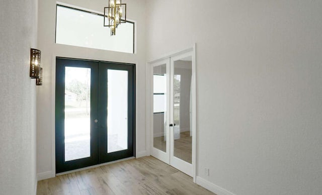 interior space featuring light hardwood / wood-style flooring, an inviting chandelier, and french doors