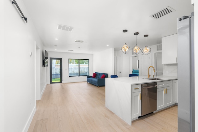 kitchen featuring light hardwood / wood-style floors, white cabinetry, stainless steel appliances, a barn door, and sink