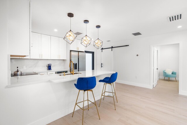 kitchen with decorative light fixtures, stainless steel fridge with ice dispenser, backsplash, and light wood-type flooring