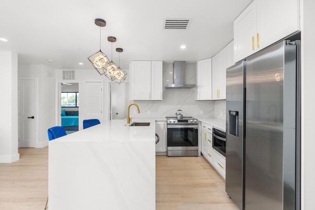 kitchen with light hardwood / wood-style floors, backsplash, wall chimney range hood, sink, and appliances with stainless steel finishes