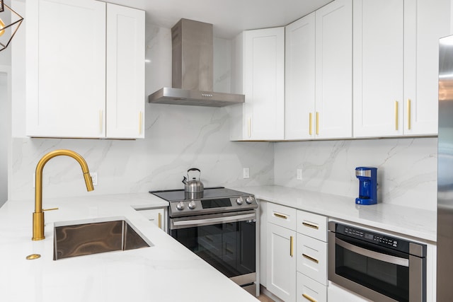 kitchen with white cabinets, wall chimney range hood, backsplash, stainless steel appliances, and sink