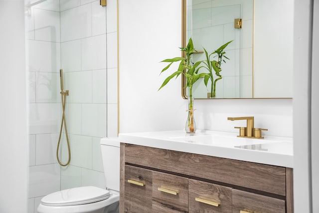 bathroom featuring a tile shower, toilet, and vanity