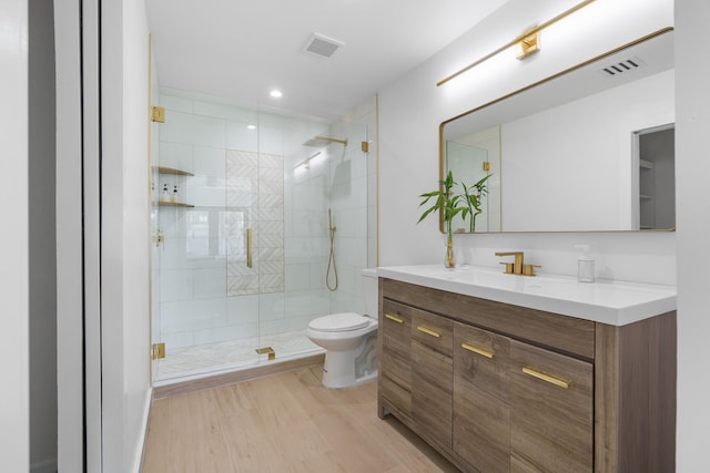 bathroom featuring a shower with door, hardwood / wood-style flooring, vanity, and toilet