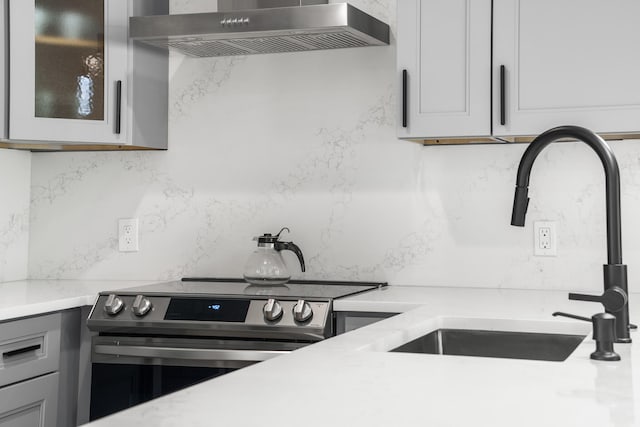 kitchen featuring sink, wall chimney exhaust hood, and electric stove