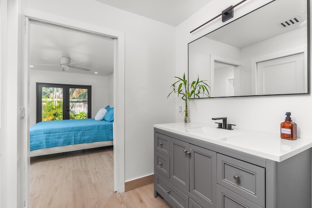 bathroom with hardwood / wood-style flooring, ceiling fan, oversized vanity, and french doors