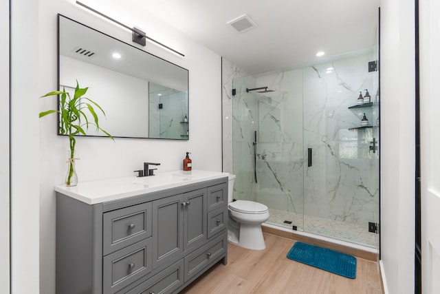 bathroom with a shower with door, vanity, toilet, and hardwood / wood-style flooring