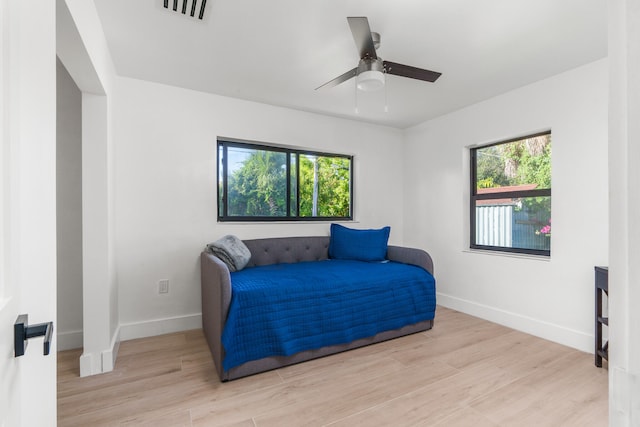 bedroom with ceiling fan, light hardwood / wood-style flooring, and multiple windows