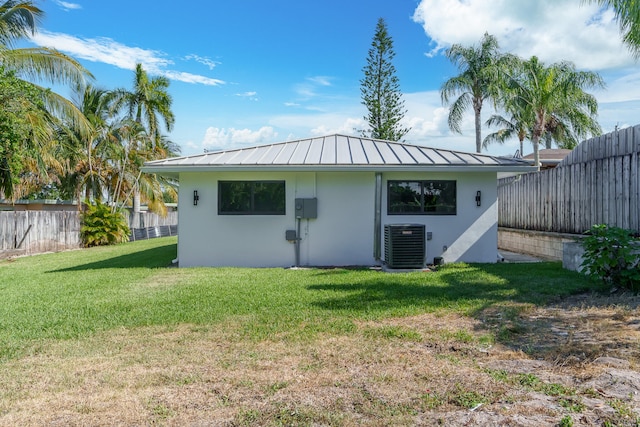 back of property with central AC and a lawn