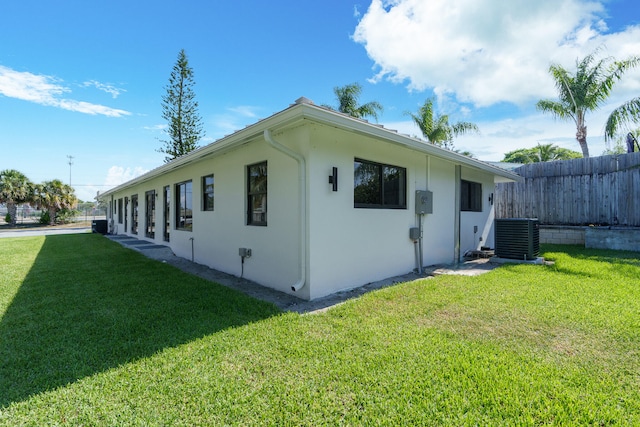 view of side of property featuring central AC and a lawn