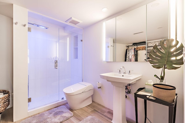 bathroom with toilet, hardwood / wood-style floors, walk in shower, and sink