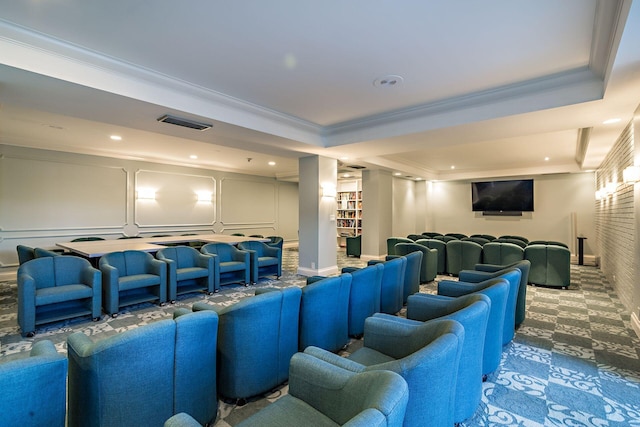 carpeted home theater room with crown molding and a tray ceiling