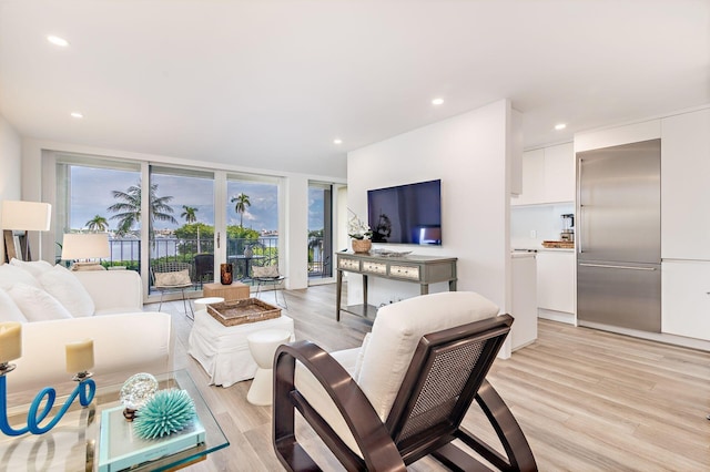 living room with a wall of windows and light hardwood / wood-style flooring