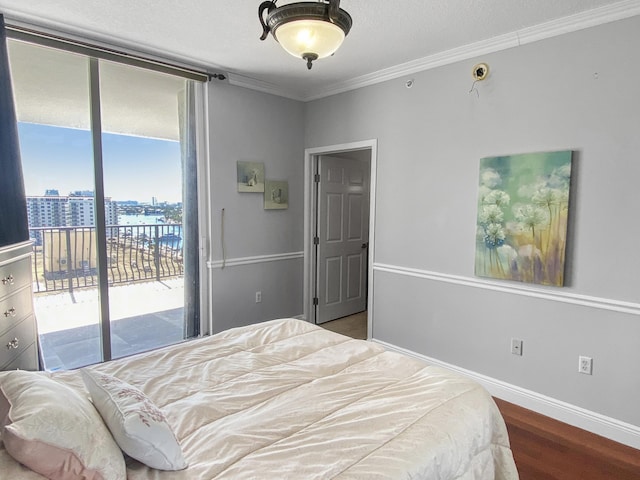 bedroom with a view of city, crown molding, wood finished floors, access to outside, and baseboards