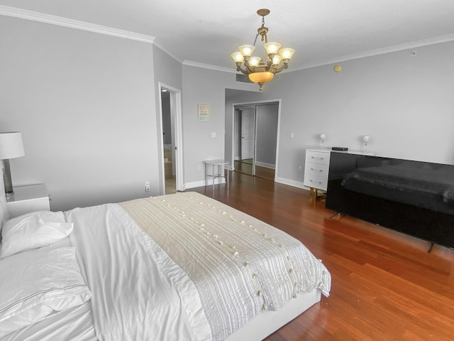 bedroom featuring baseboards, ornamental molding, wood finished floors, and an inviting chandelier