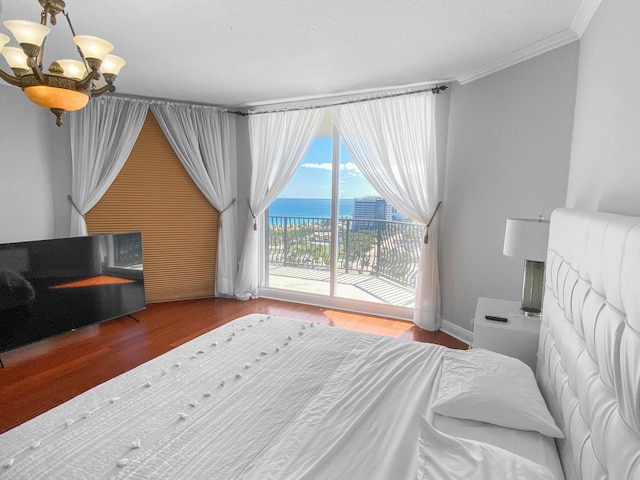 bedroom with ornamental molding, wood finished floors, a water view, access to exterior, and a notable chandelier