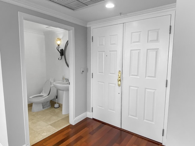 half bathroom featuring baseboards, visible vents, toilet, ornamental molding, and wood finished floors