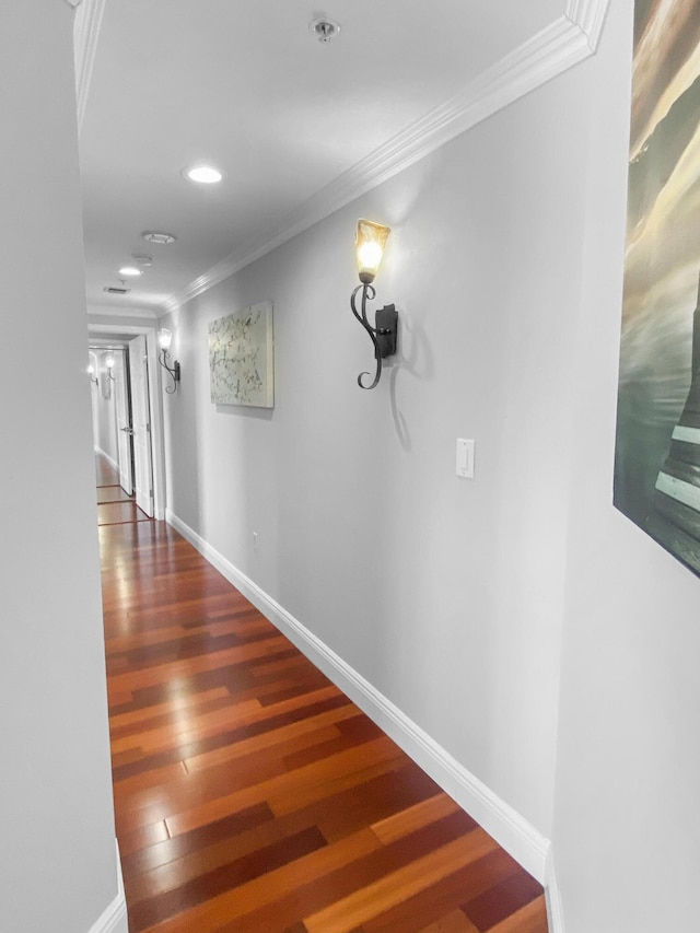 corridor with baseboards, ornamental molding, and wood finished floors