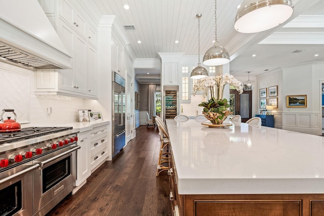 kitchen featuring a spacious island, a breakfast bar, high quality appliances, custom range hood, and pendant lighting