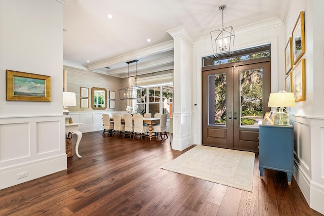 foyer entrance with an inviting chandelier, dark hardwood / wood-style floors, ornamental molding, and french doors