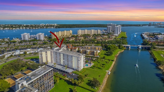 aerial view at dusk featuring a water view