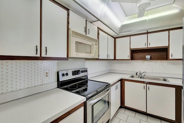 kitchen featuring sink, white cabinets, backsplash, stainless steel range with electric stovetop, and light tile patterned floors