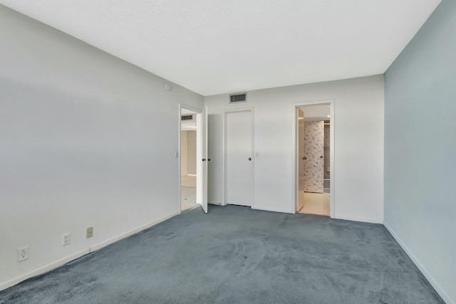 unfurnished bedroom with connected bathroom and dark carpet