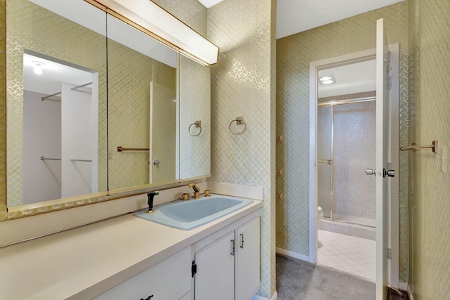 bathroom with vanity, toilet, a shower with shower door, and tile patterned flooring