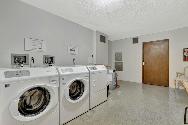 washroom with electric water heater, washer and dryer, and a textured ceiling