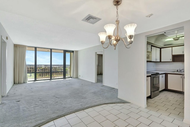 kitchen featuring stainless steel electric range oven, white cabinets, a wall of windows, hanging light fixtures, and light colored carpet