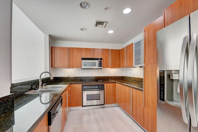 kitchen featuring light hardwood / wood-style floors, stainless steel appliances, sink, and dark stone counters