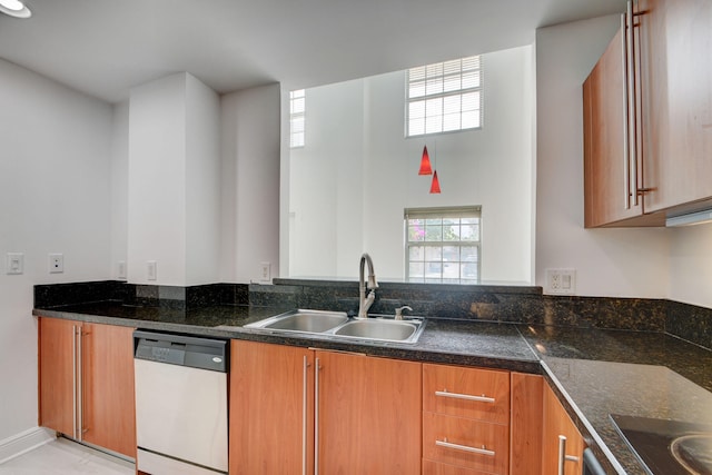 kitchen with white dishwasher, sink, black cooktop, and dark stone counters