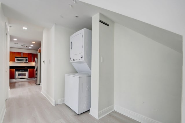 clothes washing area with light hardwood / wood-style flooring and stacked washing maching and dryer