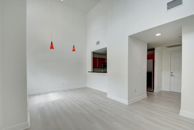 spare room featuring light hardwood / wood-style flooring and a high ceiling