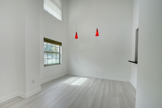 empty room featuring a high ceiling and light wood-type flooring