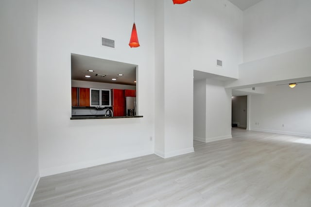 unfurnished living room featuring light hardwood / wood-style flooring and a high ceiling