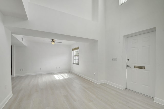 entryway featuring light hardwood / wood-style floors, a towering ceiling, and ceiling fan