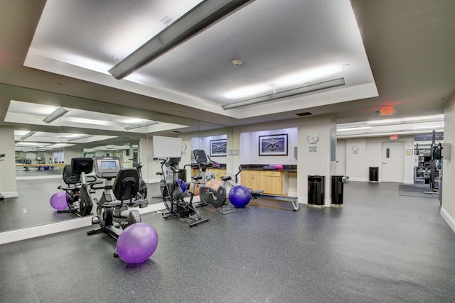 gym featuring a textured ceiling and a raised ceiling