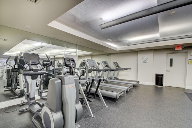 gym featuring a textured ceiling and a tray ceiling