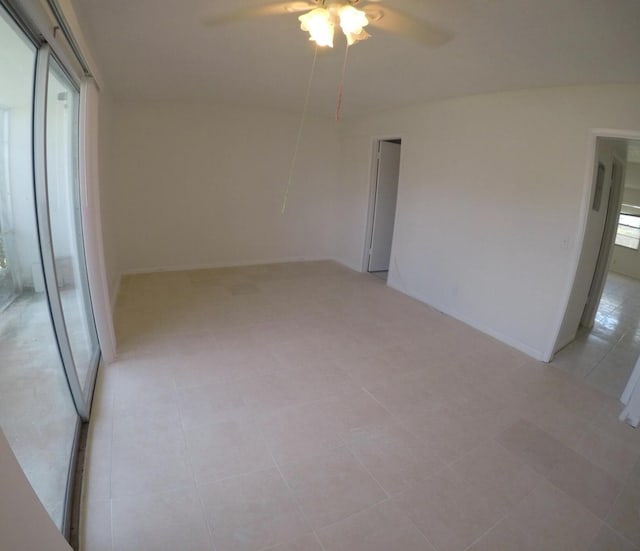 empty room with ceiling fan and light tile floors