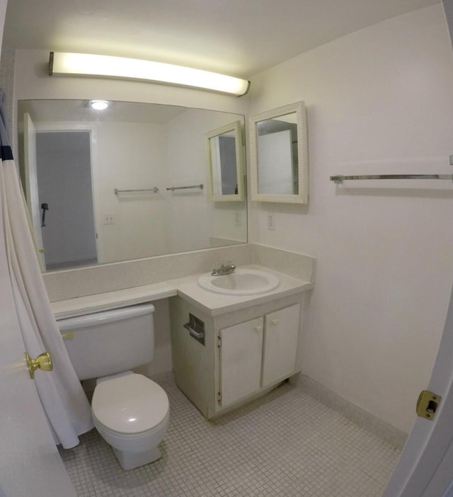 bathroom with toilet, vanity, and tile flooring