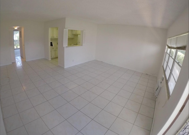 empty room with vaulted ceiling and light tile floors