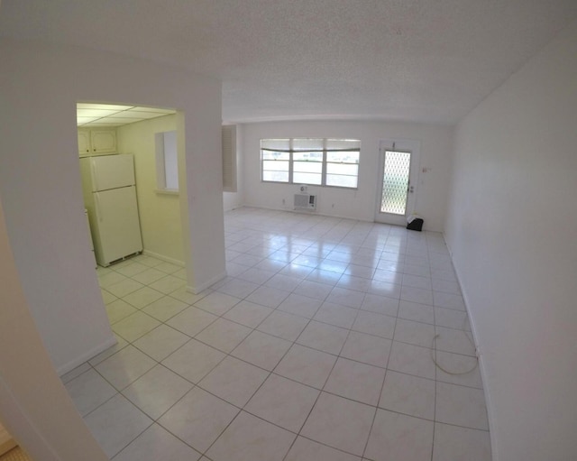 tiled empty room featuring an AC wall unit and a textured ceiling