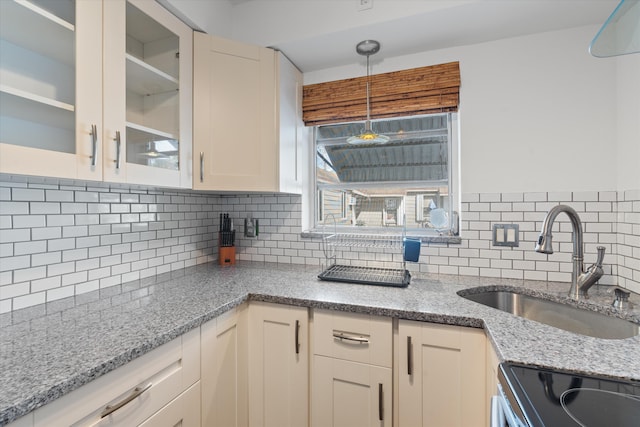 kitchen featuring sink, decorative light fixtures, light stone countertops, and backsplash