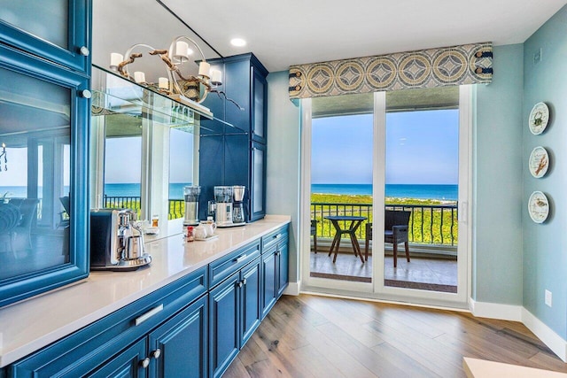 bar featuring a water view, blue cabinets, light hardwood / wood-style floors, and an inviting chandelier