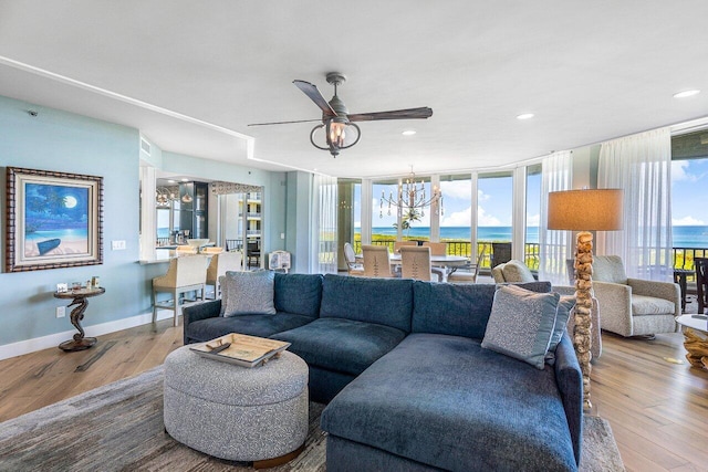 living room featuring a water view, wood-type flooring, and ceiling fan with notable chandelier