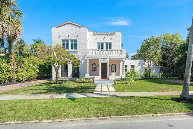 mediterranean / spanish home with a front yard and a balcony