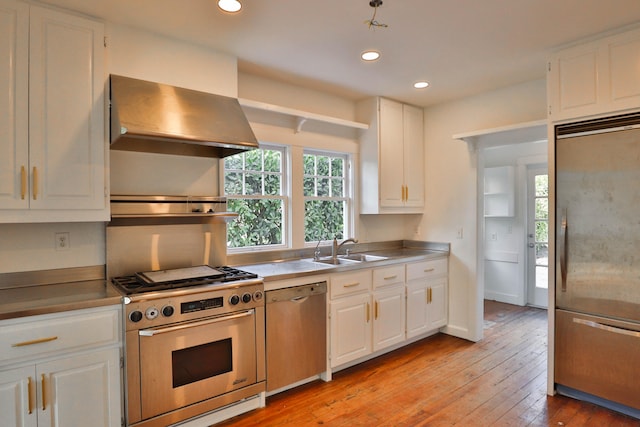 kitchen with stainless steel appliances, white cabinets, light hardwood / wood-style floors, ventilation hood, and sink