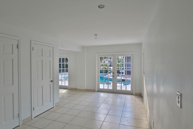 spare room featuring french doors and light tile patterned flooring